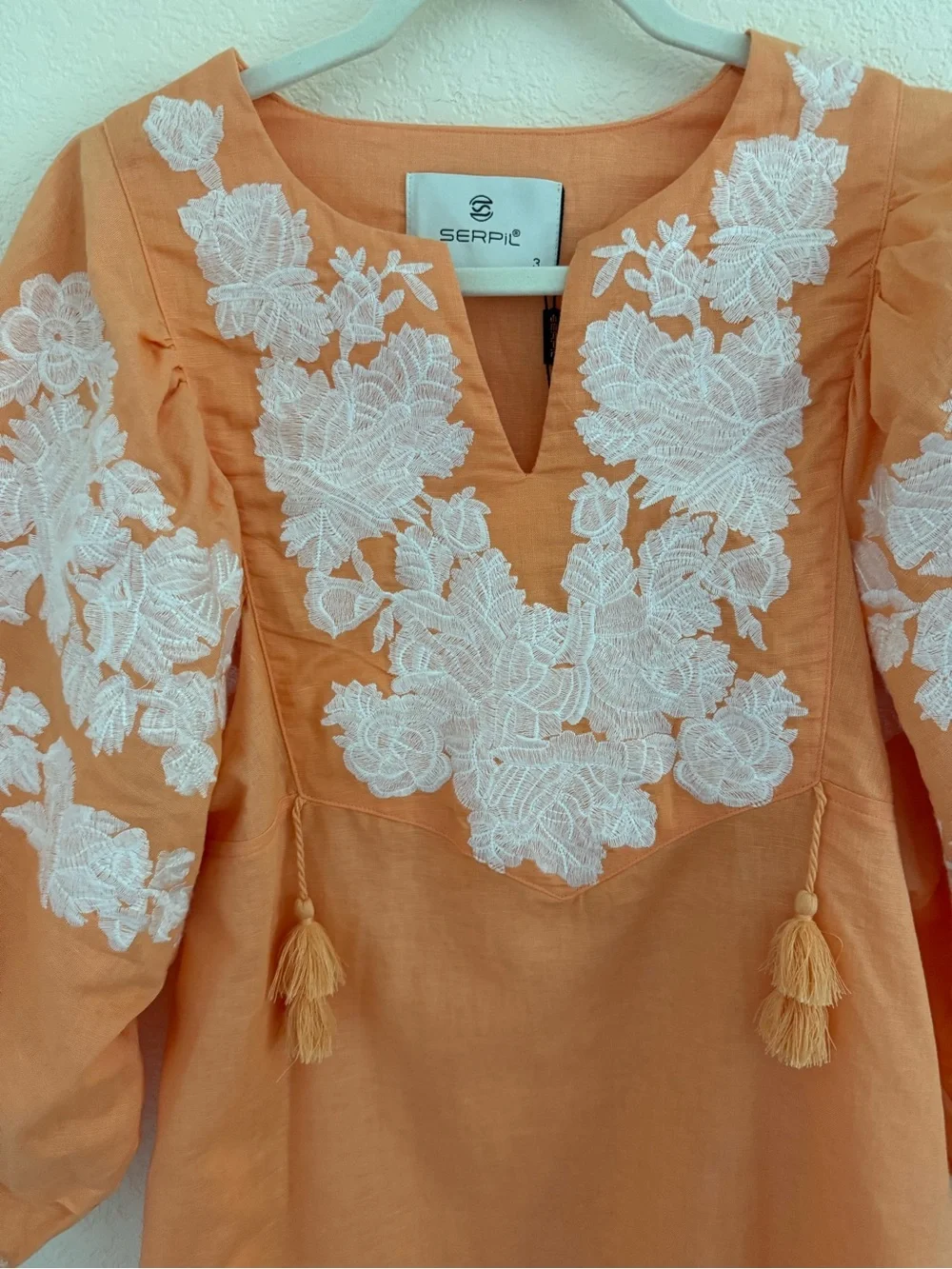 Blouse features split neckline with ties and voluminous embroidered puff sleeves